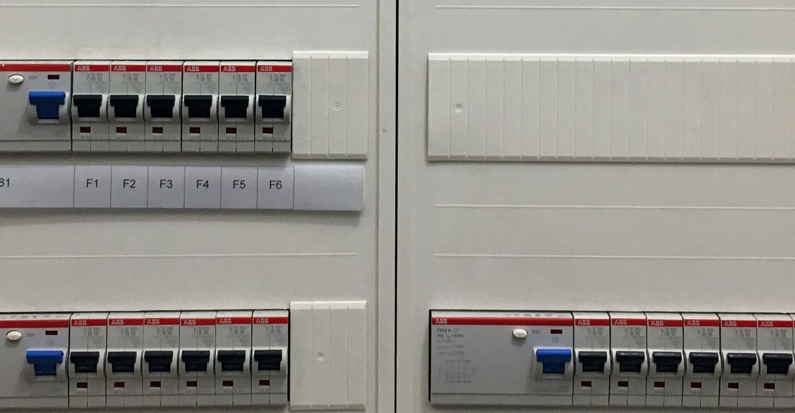 Een rij automaten met blauwe en zwarte hendels en labels in een verdeelkast